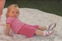 two young girls laying on a blanket in the grass